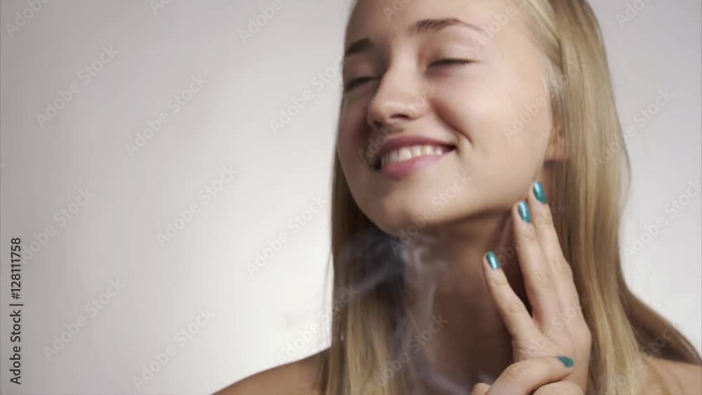 Beauty video of a young blonde pretty woman close up looking at the camera on isolated background and smoke in the air Beauty video of a young blonde pretty woman close up looking at the camera on isolated background and smoke in the air
