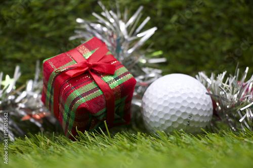 Present for golfer, golf ball and gift box on green grass background