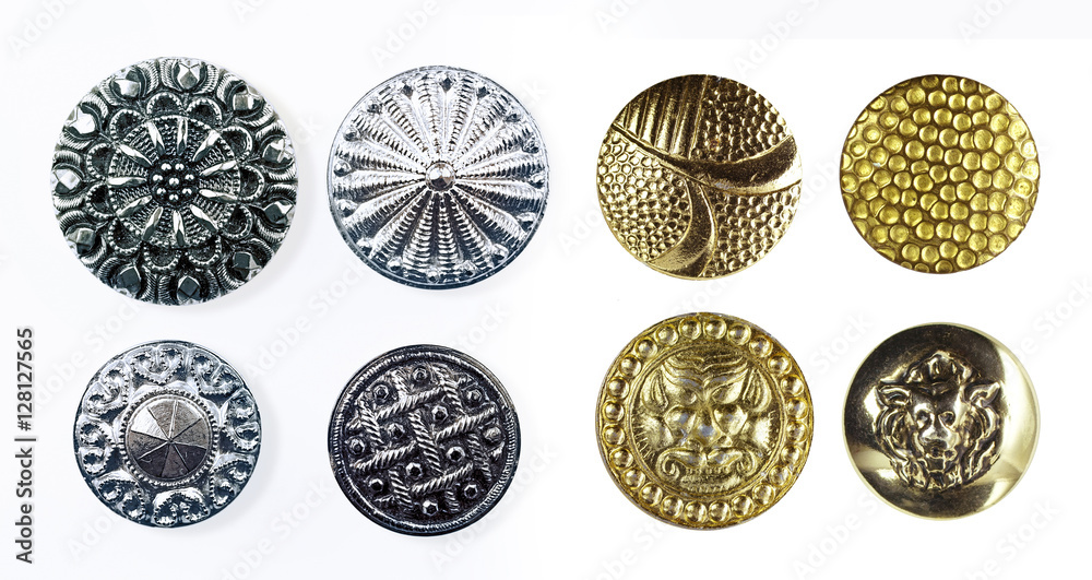 Beautiful textured metal buttons with ornaments and pictures of the silver and gold color close-up macro  isolated on white background.