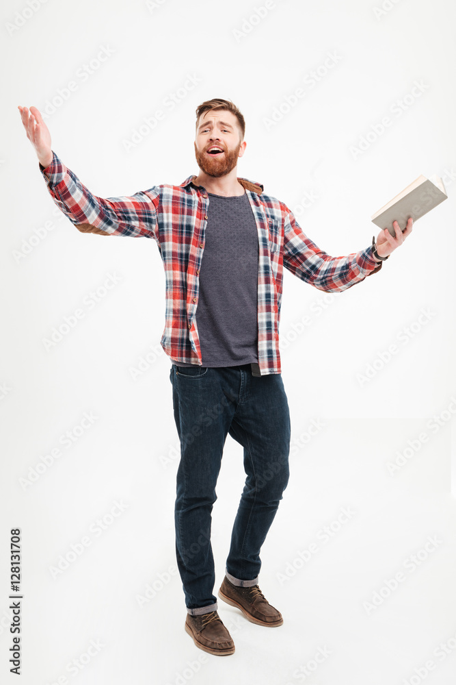 © Drobot Dean - Young bearded man holding book and gesturing with hands © Drobot Dean - Young bearded man holding book and gesturing with hands