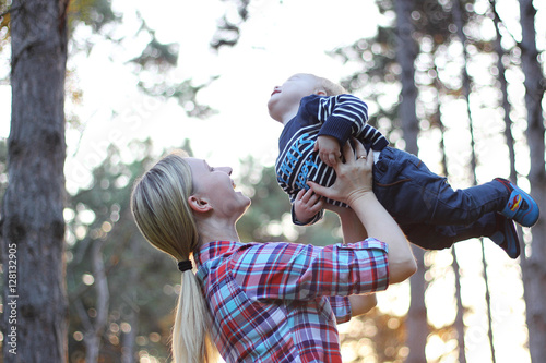 A happy family. Young mother throwing baby in nebe. photo