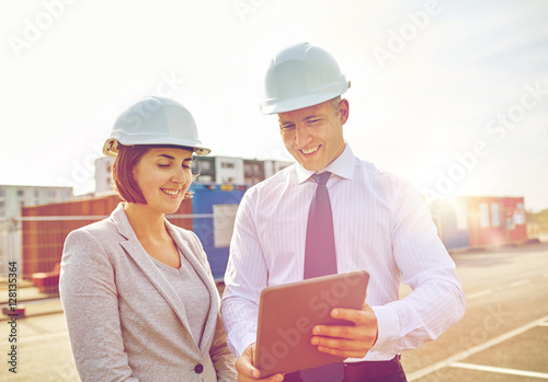 happy builders in hardhats with tablet pc outdoors