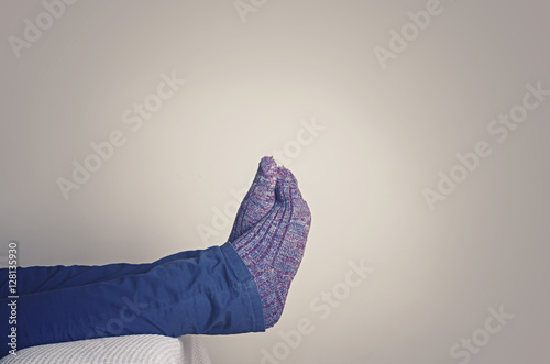 Legs with woolen socks. Man resting on sofa at home.