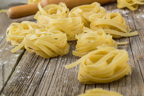 Nests of raw fettuccine pasta on the wood background