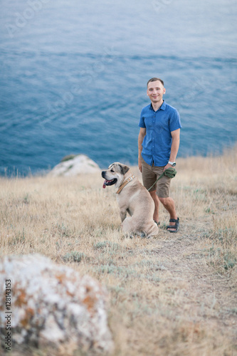 Young caucasian male walking with dog during sunrise