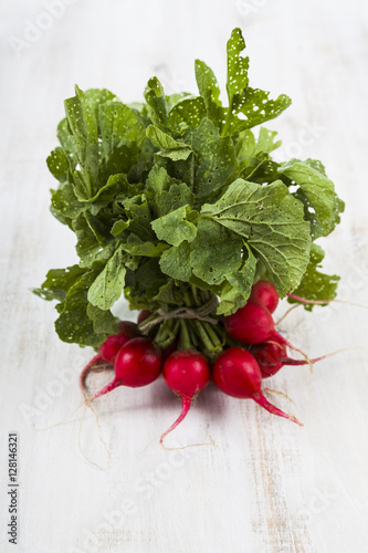 Ripe red radish with leaves on a wooden table close-up. Fresh ve