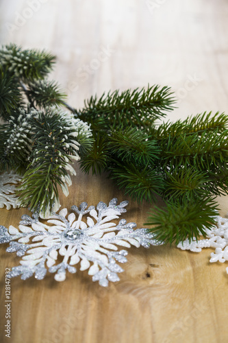 Silver snowflakes and fir branches on a wooden table. Christmas