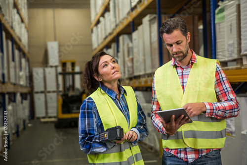 Man and a woman have short meeting in a warehouse and checking inventory levels of goods. First in first out, Last in last out, team working together concept photo. photo