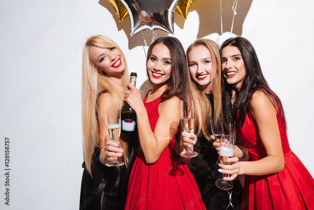 Four cheerful young women having party and drinking champagne
