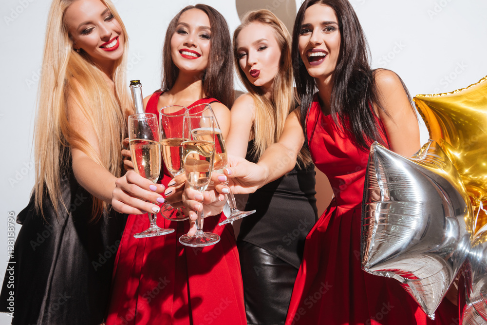 Joyful women clinking glasses and drinking champagne on the party