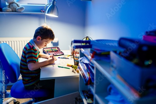 Child is doing homework in the light of the lamp