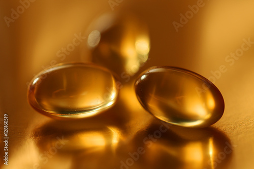 three oil capsules on blurred golden background 1