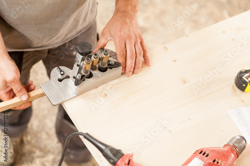 woodworker holding a jig on a wooden board photo