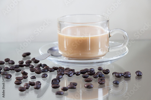 Hot coffee in glass cups and coffee beans on a glass table.