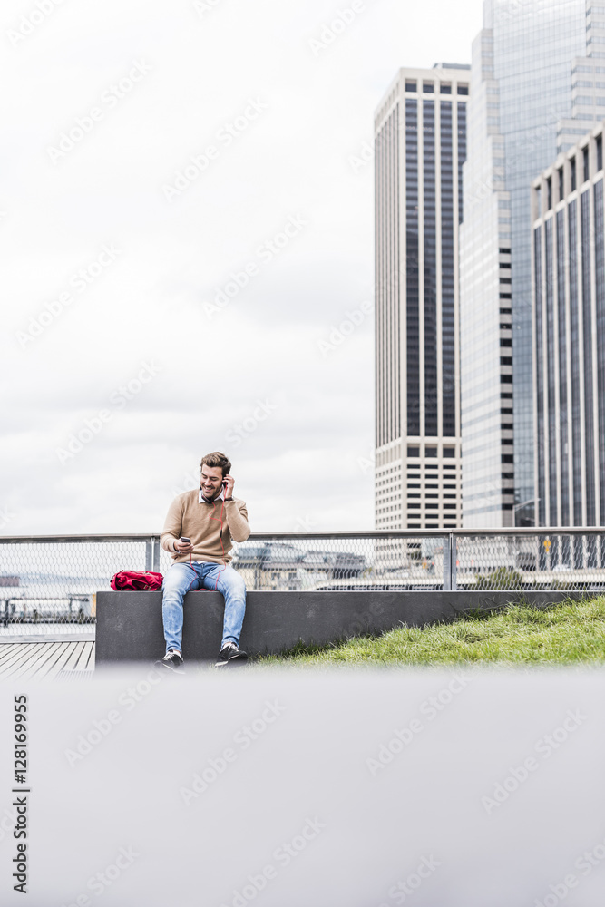 USA, New York, Businessman in Manhattan using smart phone and headphones USA, New York, Businessman in Manhattan using smart phone and headphones