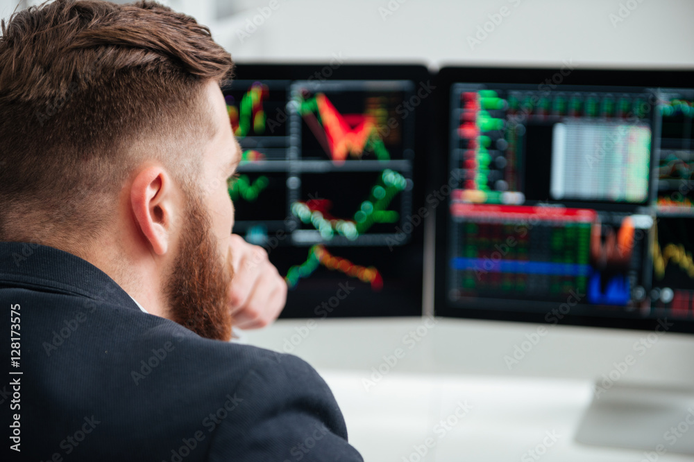 Back view of concentrated young businessman thinking and working Back view of concentrated young businessman thinking and working