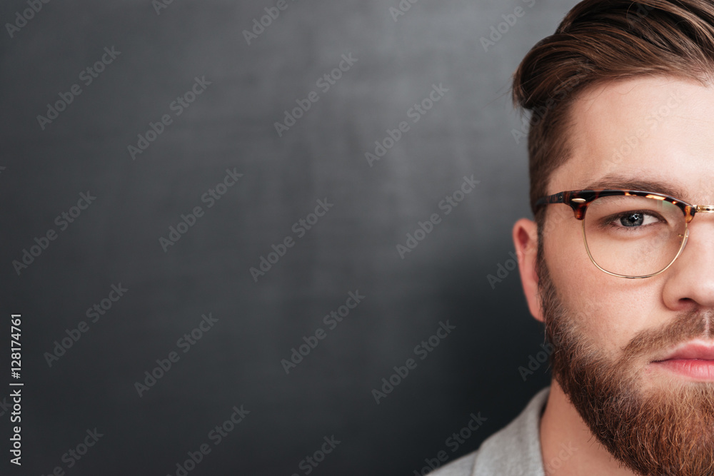 Half face of serious bearded man in glasses