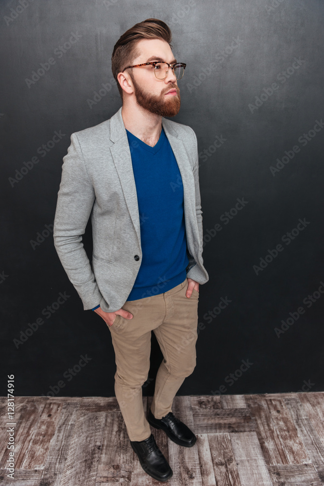 Pensive bearded young businessman standing and thinking Pensive bearded young businessman standing and thinking