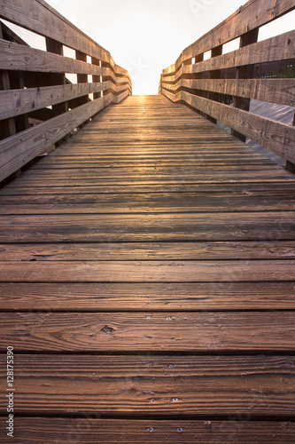 wooden beach boardwalk path at sunset leading towards light