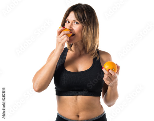 Sport woman eating an orange
