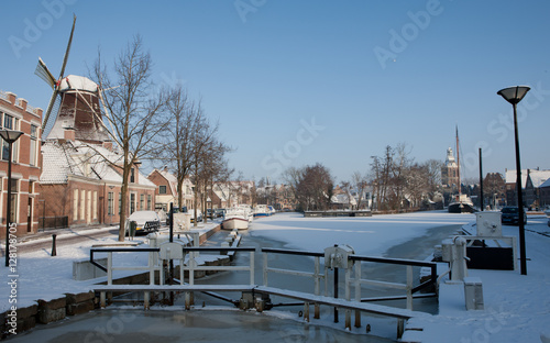 Traditional windmill in winter Meppel Drenthe Netherlands. Frozen canal Lock at Sluisgracht. Stoombootkade. photo