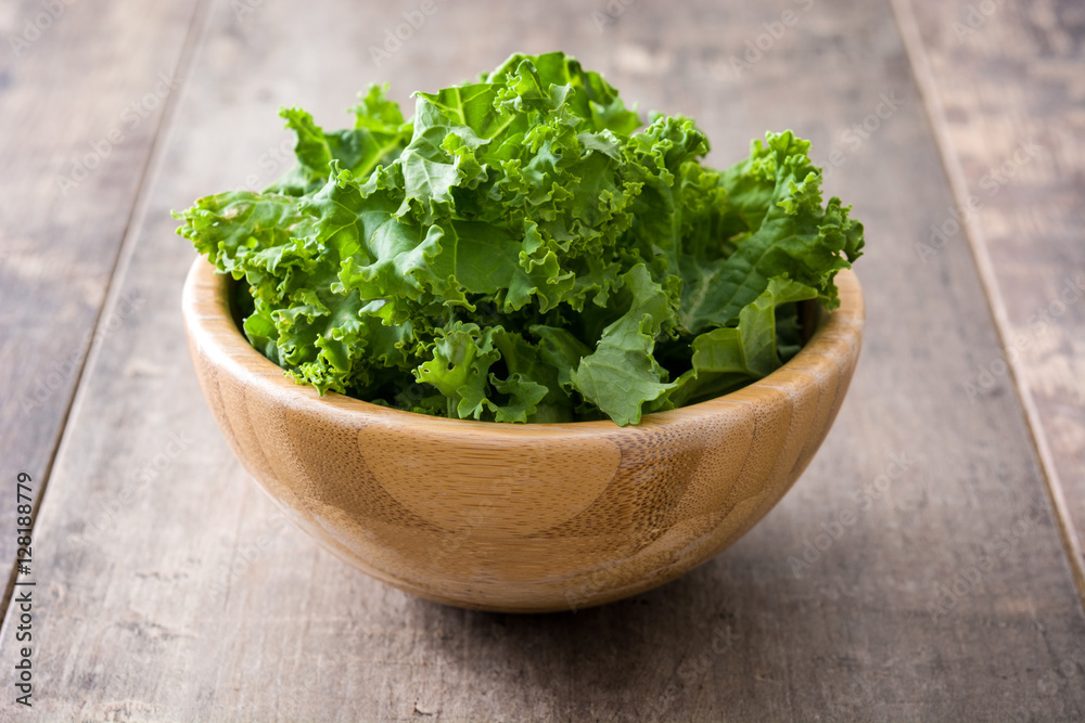 Fresh green superfood kale leaves in wooden bowl on wooden background
Fresh green superfood kale leaves in wooden bowl on wooden background