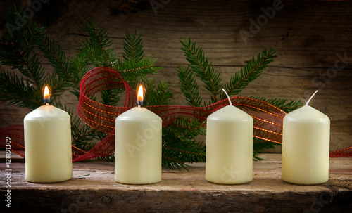 Four white candles  two of them burning on the second advent  christmas decoration on a rustic board 