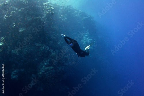 Freediver moves underwater along coral reef