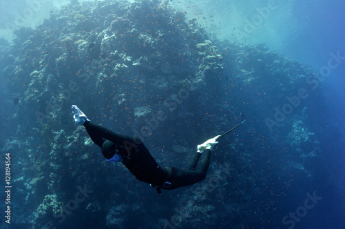 Freediver moves underwater along coral reef