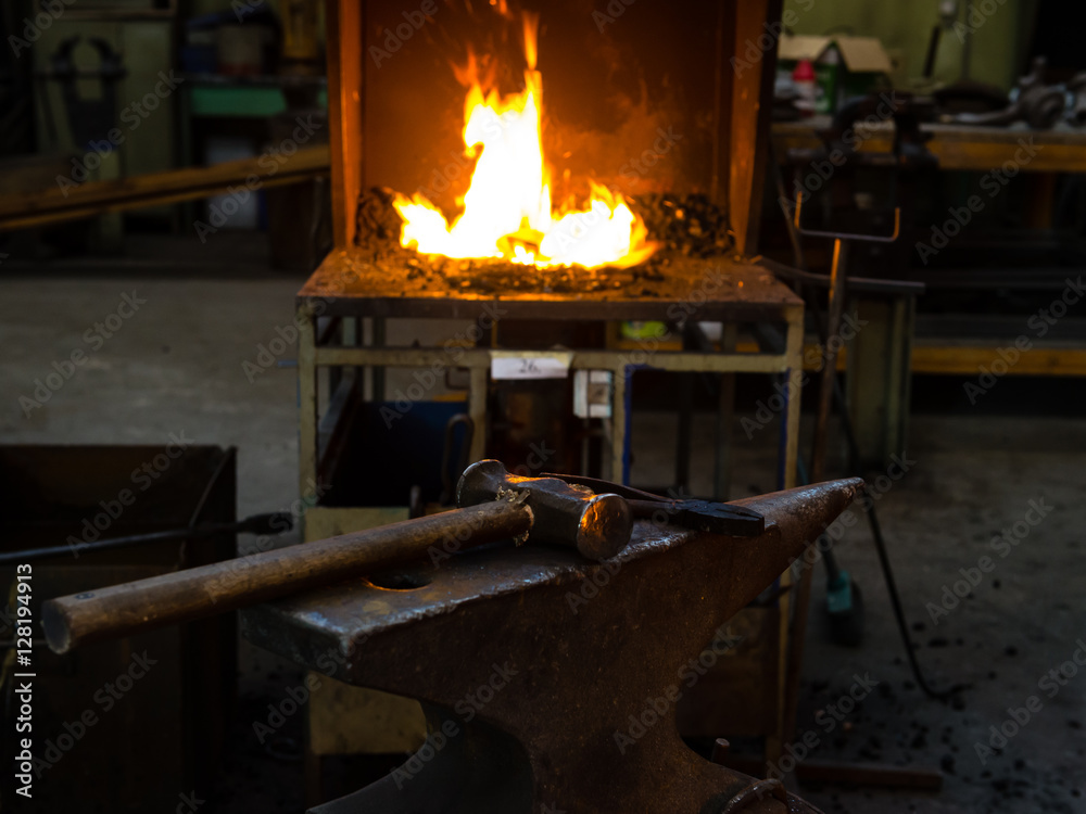 The blacksmith manually forging the molten metal on the anvil