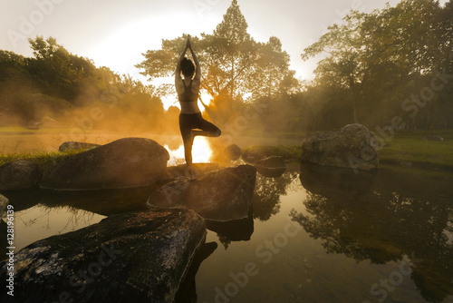 Fototapeta Naklejka Na Ścianę i Meble -  Young woman in silhouette practice yoga in a hot spring