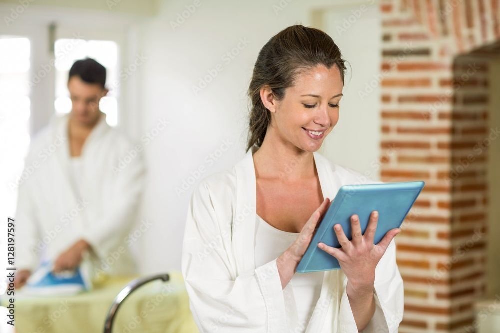 Beautiful woman in bathrobe using digital tablet