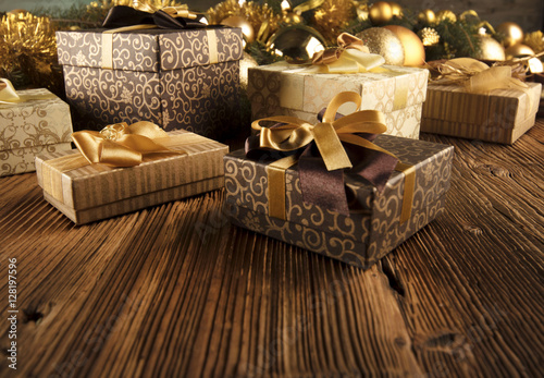 Golden Christmas decoration. Presents in boxes on a wooden background with copy space. Golden baubles. Christmas theme. Golden and brownish aesthetics. Christmas spices. © zolnierek