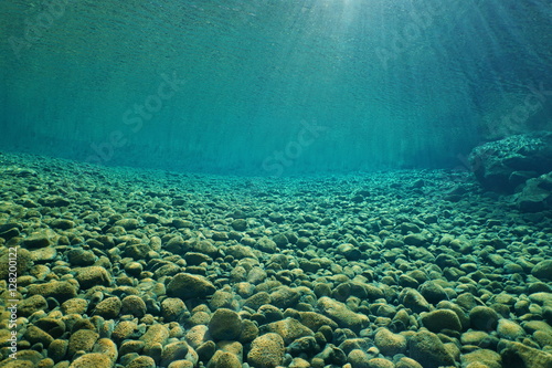 Pebbles underwater on riverbed with clear freshwater and sunlight through water surface, natural scene, Dumbea river, New Caledonia, south Pacific