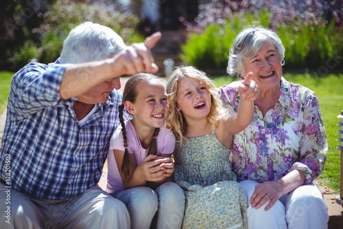 Cheerful girls with grandparents while sitting in back yard