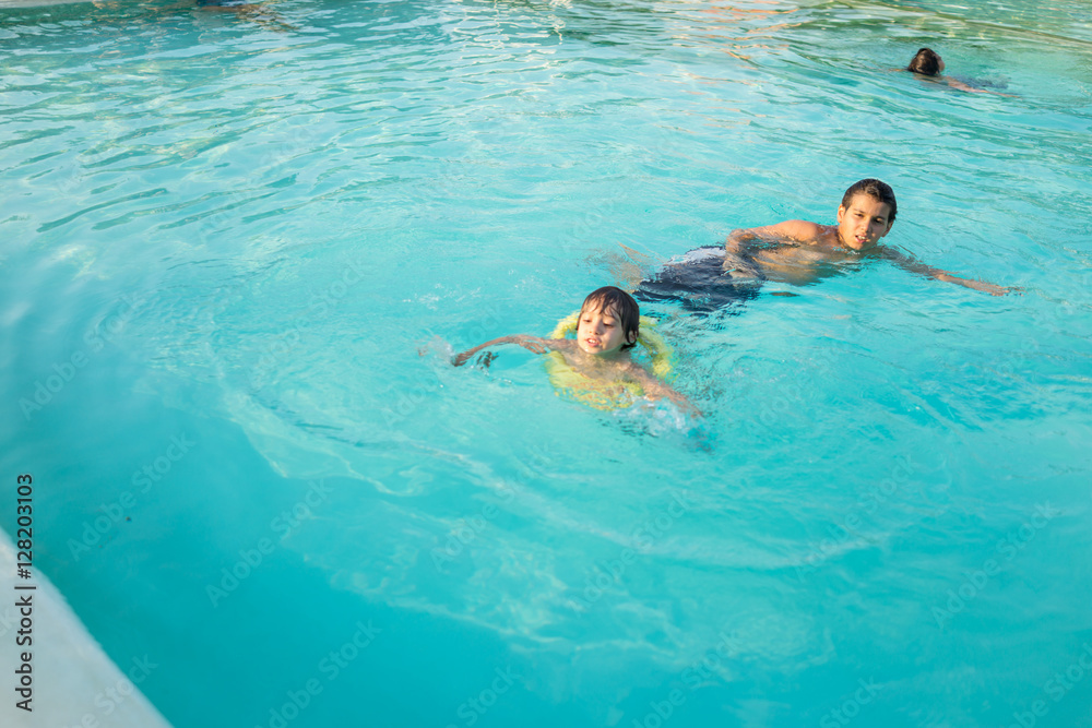 Young boy kid child splashing in swimming pool having fun leisur Young boy kid child splashing in swimming pool having fun leisur