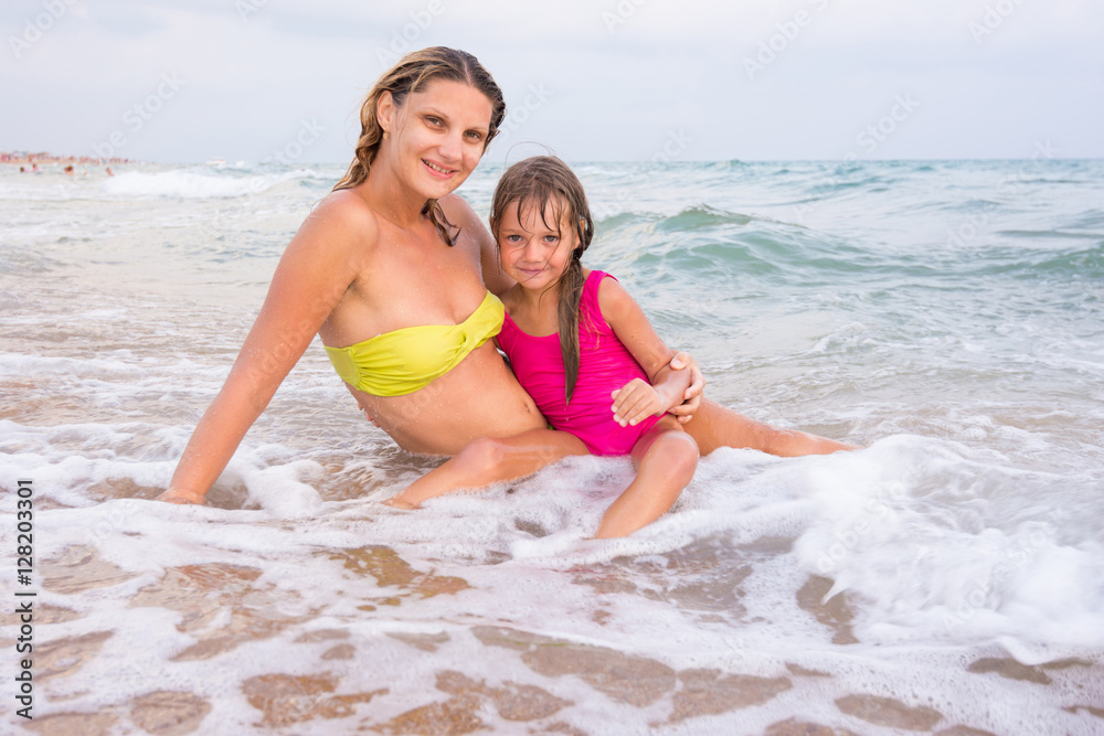 My mother and five year old daughter, sitting in the shallow water at the seaside My mother and five year old daughter, sitting in the shallow water at the seaside