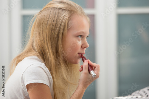 Cute little girl with lipstick applying makeup 