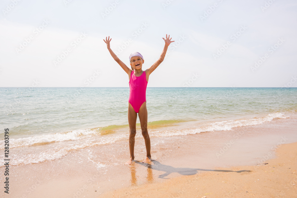 Happy girl lifted her arms up on the sandy shore of the sea Happy girl lifted her arms up on the sandy shore of the sea