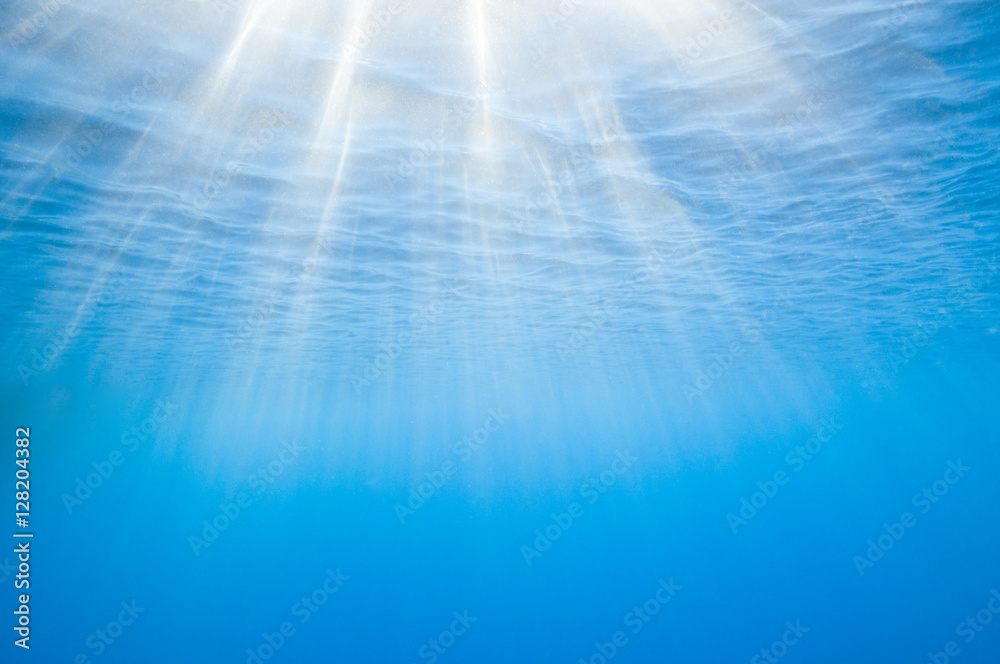 Sunbeams penetrating blue ocean background.