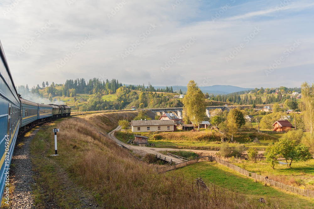 Obraz premium View from the train window at the sunlit village. Carpathians, U