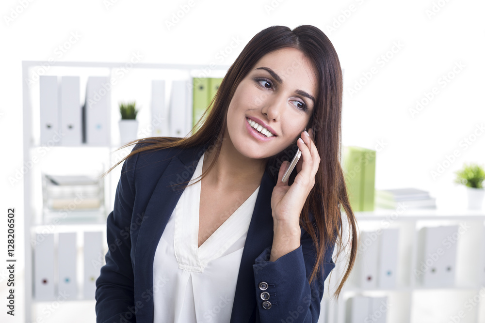 Close up of a smiling businesswoman on her cell phone in a white Close up of a smiling businesswoman on her cell phone in a white