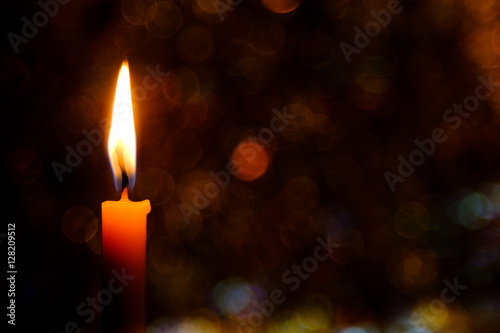 Candle flame light at night with abstract circular bokeh background Christmas lights. photo