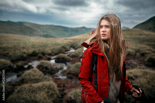 Shot of a young woman looking at the landscape while hiking in the mountains.Outdoor shot of attractive young woman with backpack standing in a mountain stream. Female hiker in creek water. © Serhii