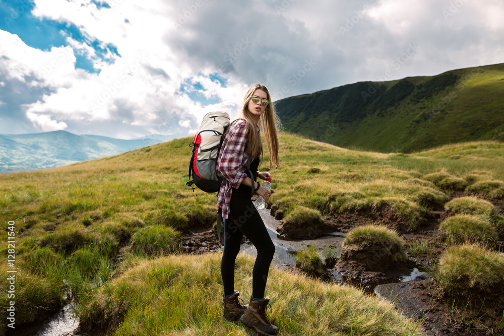 Shot of a young woman looking at the landscape while hiking in the mountains.Outdoor shot of attractive young woman with backpack standing in a mountain stream. Female hiker in creek water.