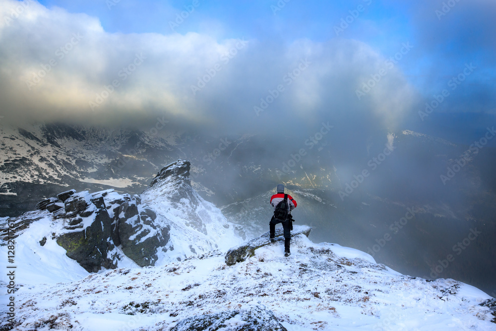 Hiker standing on a rock.Winter landscape.Climber on the snowy mountains.Travel inspiration and motivation, beautiful landscape.Active sport concept