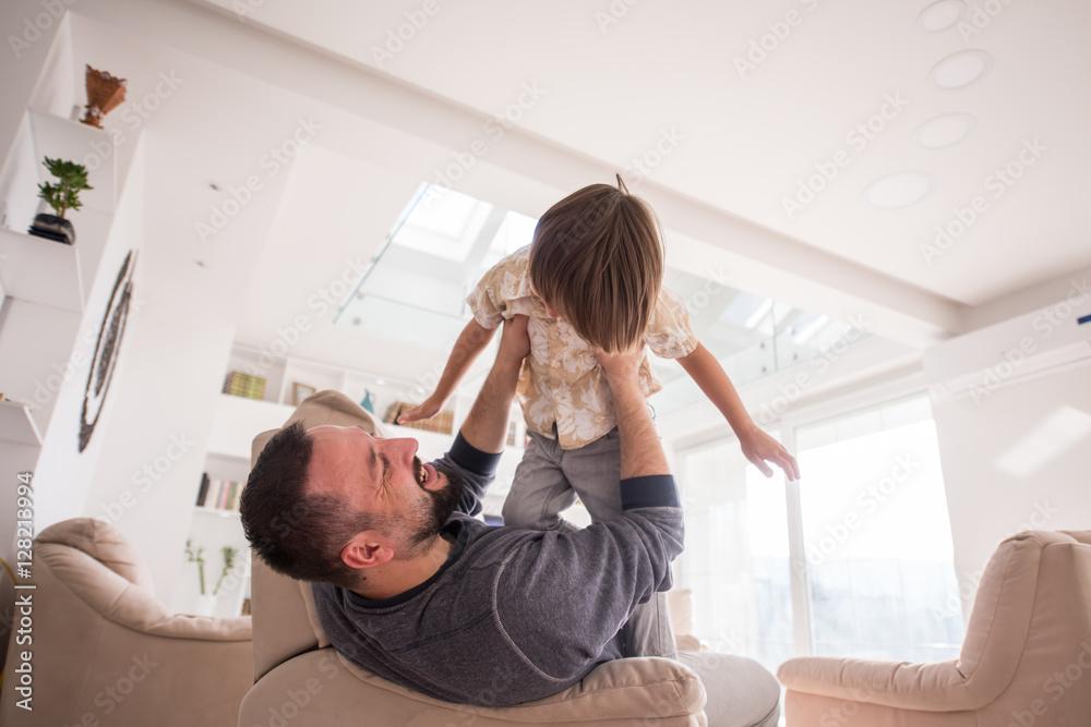 Cheerful young boy having fun with father on sofa Cheerful young boy having fun with father on sofa