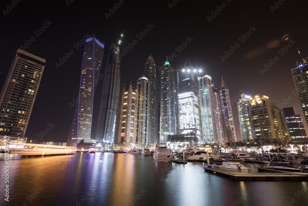 Architecture theme. Dubai marina. Luxurious travel and living, business and finance theme. Luxurious apartments. High value property. Night lights. Illuminated skyline. Big construction site.