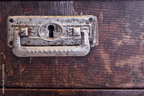 Old wooden drawer with ornate pewter handles. © okrip