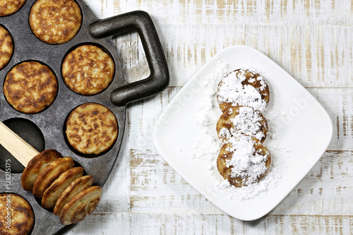 homemade Dutch poffertjes baked in a traditional cast iron pan on wooden background 